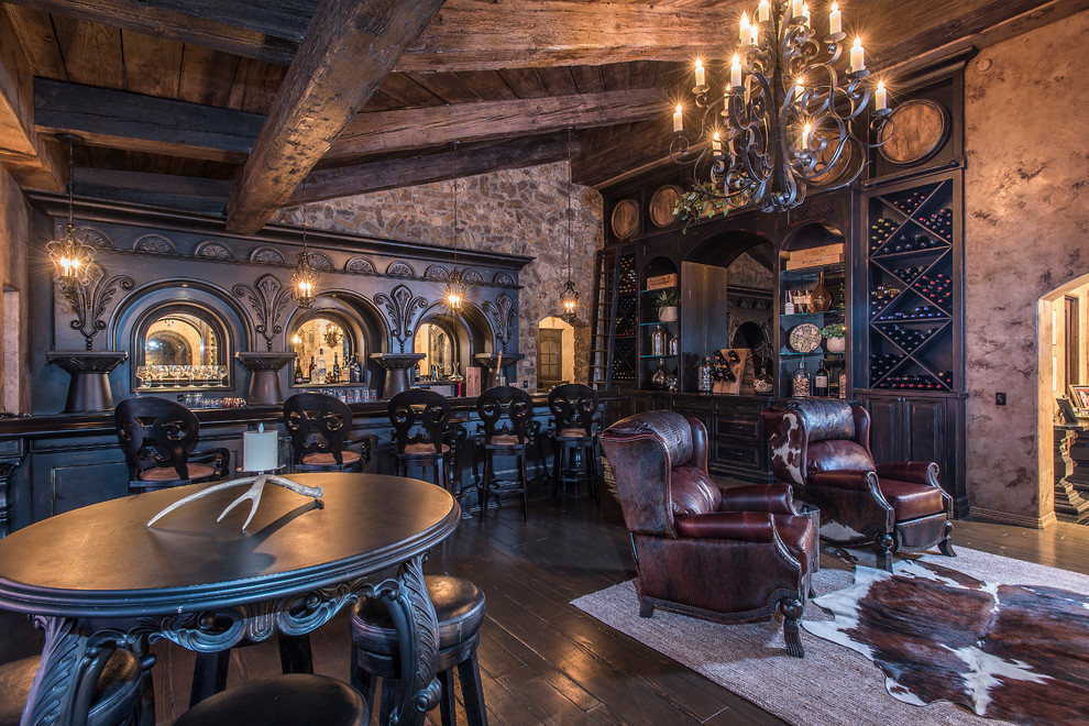 Cette photo montre un très grand bar de salon parallèle méditerranéen en bois foncé avec des tabourets, un placard avec porte à panneau surélevé, une crédence miroir, parquet foncé et un sol marron.