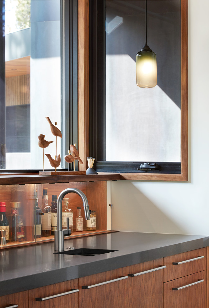 Photo of a large modern single-wall wet bar in San Francisco with a submerged sink, flat-panel cabinets, dark wood cabinets, engineered stone countertops, brown splashback and wood splashback.
