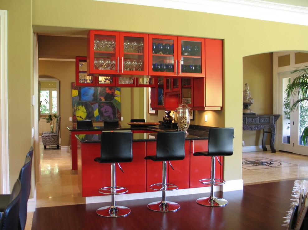 Cette photo montre un bar de salon asiatique avec des portes de placard rouges, un plan de travail en granite, des tabourets, un placard à porte plane, parquet foncé et un sol marron.