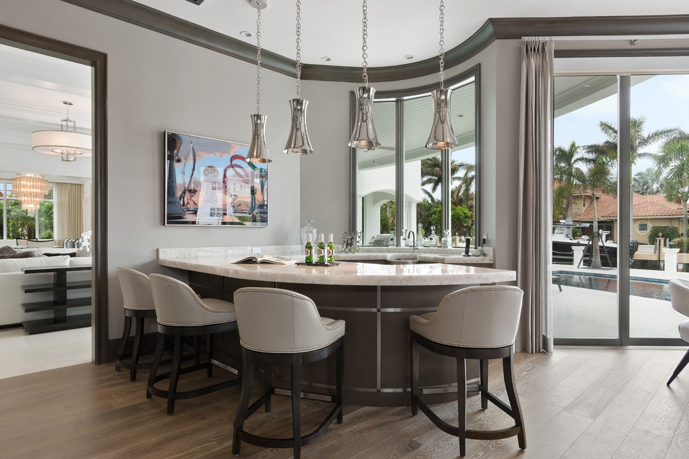 Klassische Hausbar in U-Form mit Bartresen, Unterbauwaschbecken, braunem Boden, Küchenrückwand in Grau und weißer Arbeitsplatte in Miami