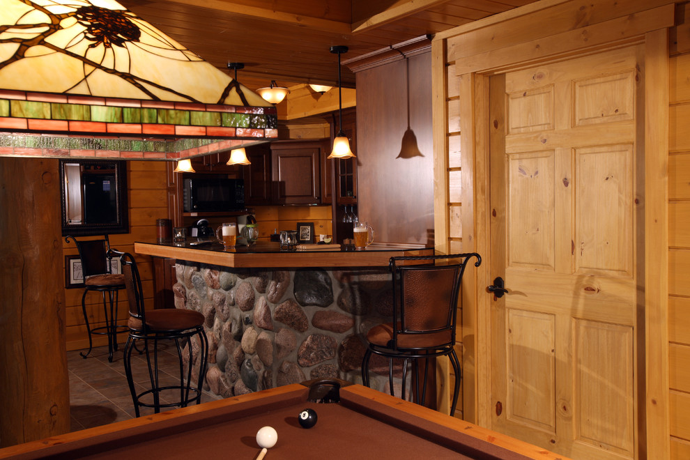 Cette photo montre un bar de salon montagne en L et bois foncé de taille moyenne avec des tabourets, un placard avec porte à panneau surélevé, un plan de travail en surface solide et un sol en carrelage de céramique.
