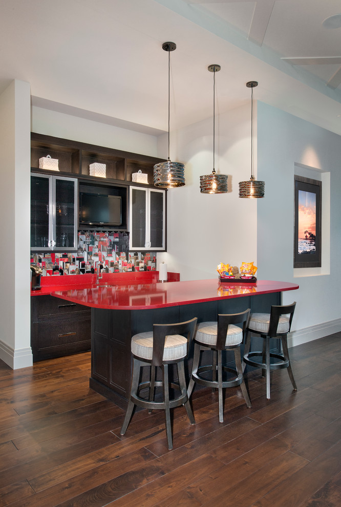 Esempio di un bancone bar contemporaneo con ante di vetro, paraspruzzi multicolore, parquet scuro, ante in legno bruno, top in quarzo composito e top rosso
