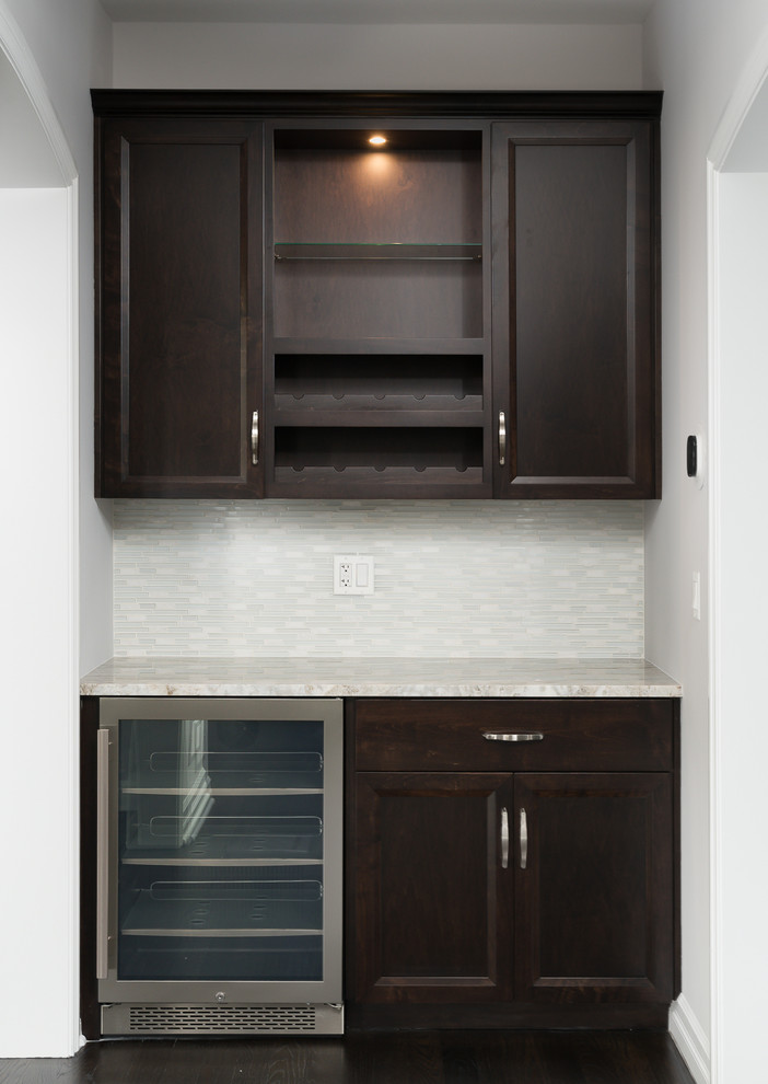 Design ideas for a small traditional galley wet bar in Chicago with no sink, recessed-panel cabinets, dark wood cabinets, granite worktops, white splashback, metro tiled splashback, dark hardwood flooring and brown floors.