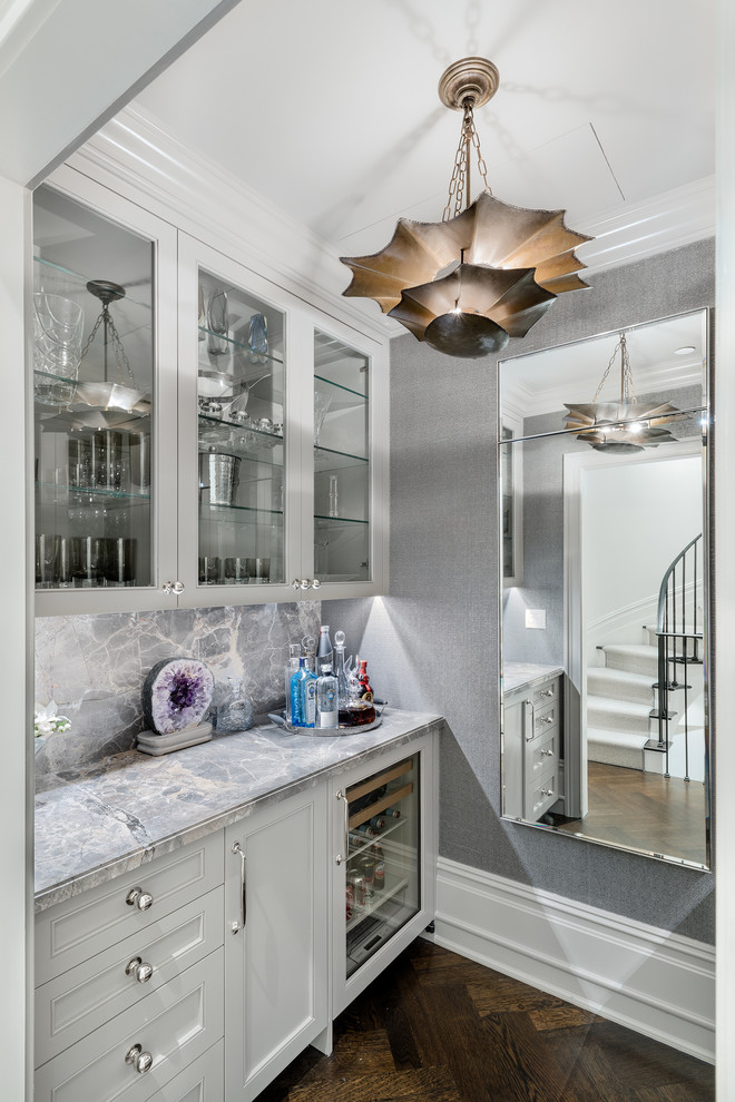 Home bar - small transitional single-wall dark wood floor and brown floor home bar idea in New York with glass-front cabinets, white cabinets and gray backsplash