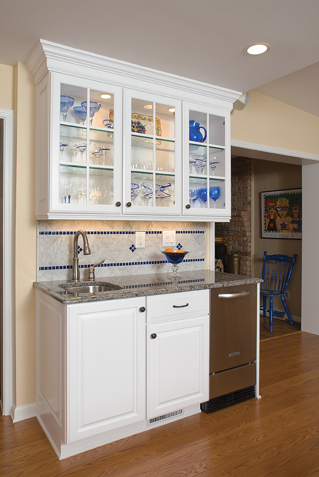 Inspiration for a small timeless single-wall medium tone wood floor wet bar remodel in Atlanta with an undermount sink, raised-panel cabinets, white cabinets, granite countertops, beige backsplash and ceramic backsplash