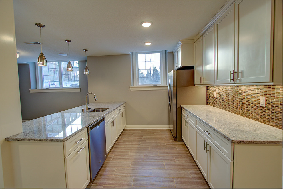 Photo of a large classic galley wet bar in Milwaukee with a built-in sink, recessed-panel cabinets, white cabinets, granite worktops, multi-coloured splashback and ceramic flooring.