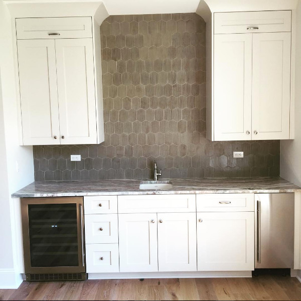 Inspiration for a mid-sized modern single-wall medium tone wood floor and beige floor wet bar remodel in Jacksonville with an undermount sink, recessed-panel cabinets, white cabinets, quartz countertops, gray backsplash and porcelain backsplash