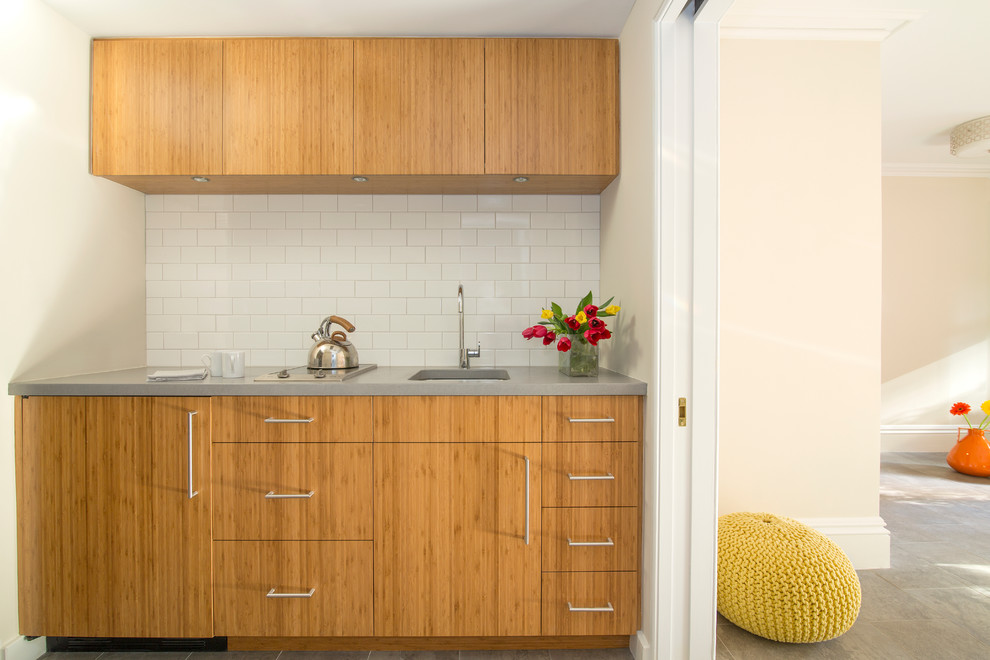 Small contemporary single-wall wet bar in New York with a submerged sink, flat-panel cabinets, medium wood cabinets, concrete worktops, white splashback, ceramic splashback and porcelain flooring.