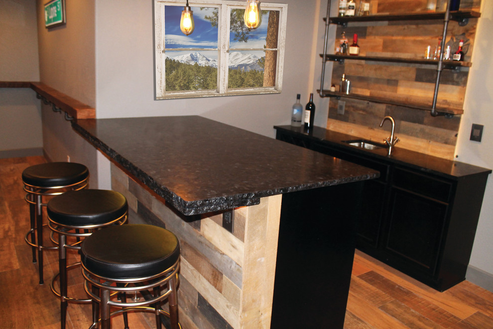 This is an example of a rustic wet bar in Denver with a submerged sink, black cabinets, granite worktops, black splashback and medium hardwood flooring.