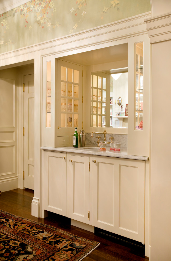 Modelo de bar en casa con fregadero lineal clásico pequeño con fregadero bajoencimera, armarios con paneles empotrados, puertas de armario blancas y suelo de madera en tonos medios