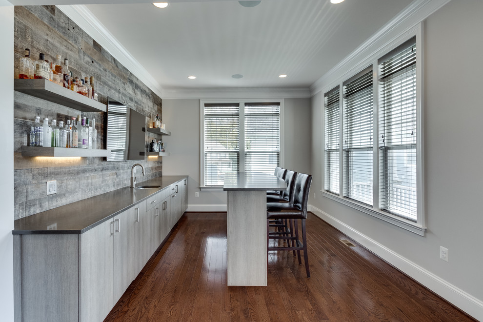 Example of a large trendy single-wall medium tone wood floor and brown floor wet bar design in DC Metro with an undermount sink, flat-panel cabinets, gray cabinets, gray backsplash and wood backsplash