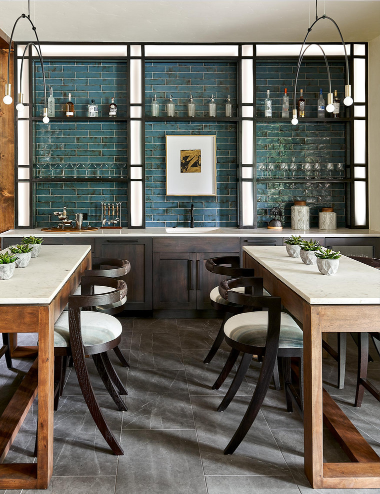 This is an example of a large rustic single-wall wet bar in Denver with an integrated sink, dark wood cabinets, composite countertops, metro tiled splashback, slate flooring, grey floors, white worktops, shaker cabinets, green splashback and feature lighting.