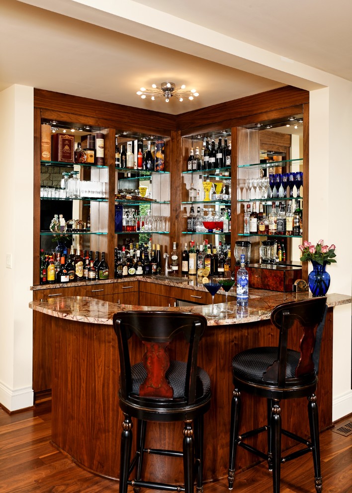 Modelo de bar en casa con barra de bar en L clásico renovado extra grande con armarios con paneles lisos, puertas de armario de madera oscura y suelo de madera en tonos medios