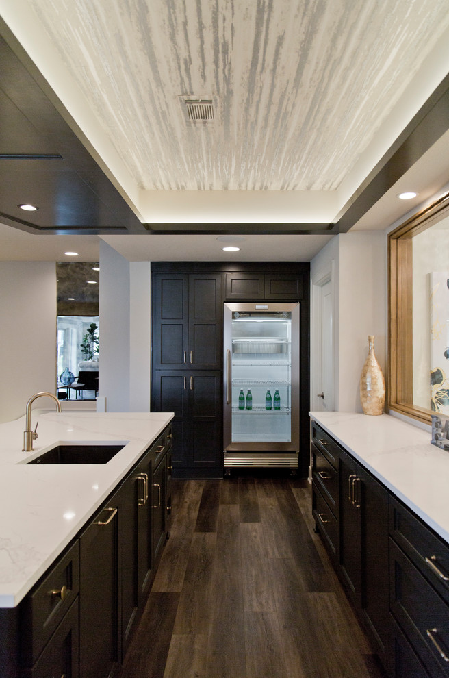 Large modern galley breakfast bar in Kansas City with a submerged sink, recessed-panel cabinets, grey cabinets, medium hardwood flooring, brown floors and white worktops.