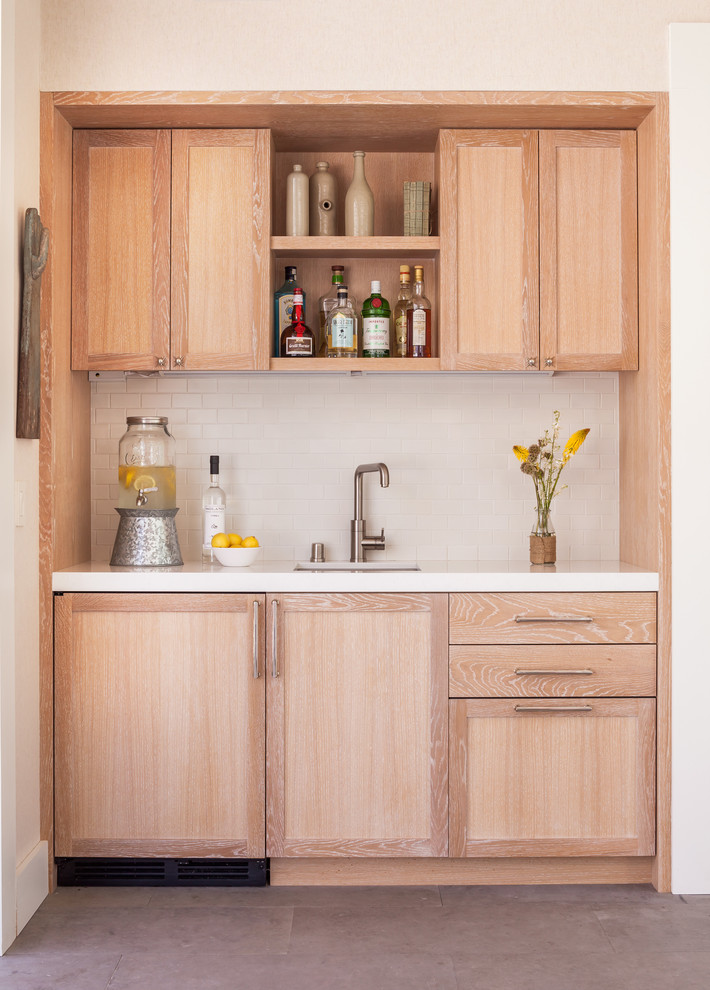 Diseño de bar en casa con fregadero lineal actual pequeño con fregadero bajoencimera, armarios con paneles empotrados, puertas de armario de madera clara y salpicadero blanco