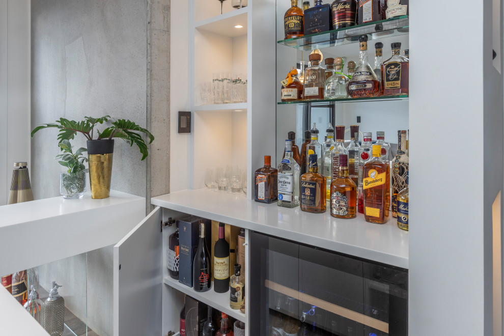 Seated home bar - large contemporary galley medium tone wood floor and brown floor seated home bar idea in Auckland with an undermount sink, flat-panel cabinets, white cabinets, solid surface countertops, mirror backsplash and yellow countertops