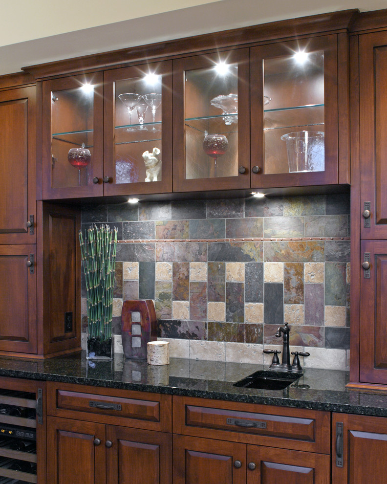 Foto di un angolo bar rustico di medie dimensioni con lavello sottopiano, ante di vetro, ante in legno scuro, top in granito, paraspruzzi multicolore, paraspruzzi con piastrelle in pietra e top nero