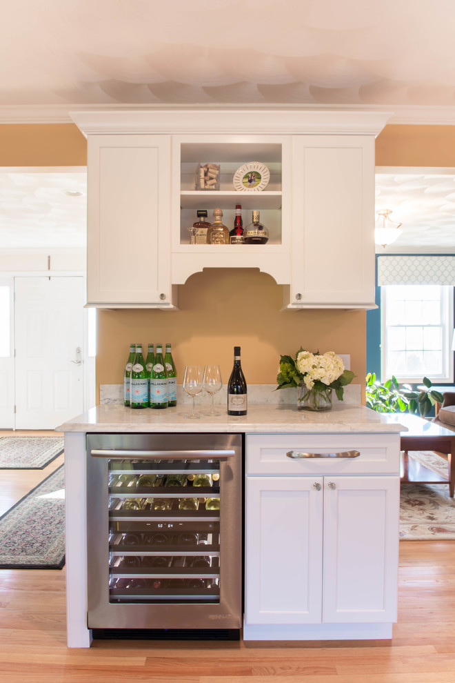 This is an example of a small traditional single-wall home bar in Providence with shaker cabinets, white cabinets, marble worktops and light hardwood flooring.