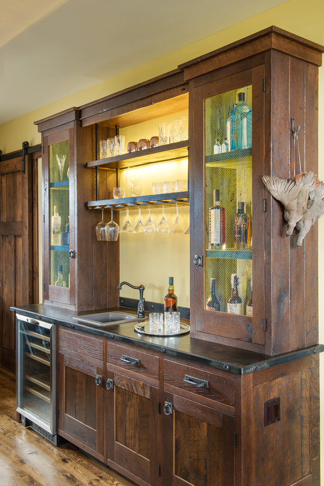 Design ideas for a rustic single-wall wet bar in Other with a built-in sink, dark wood cabinets and medium hardwood flooring.