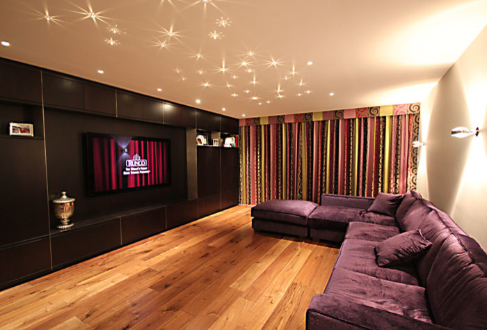 Mid-sized trendy enclosed home theater photo in Wiltshire with beige walls and a media wall