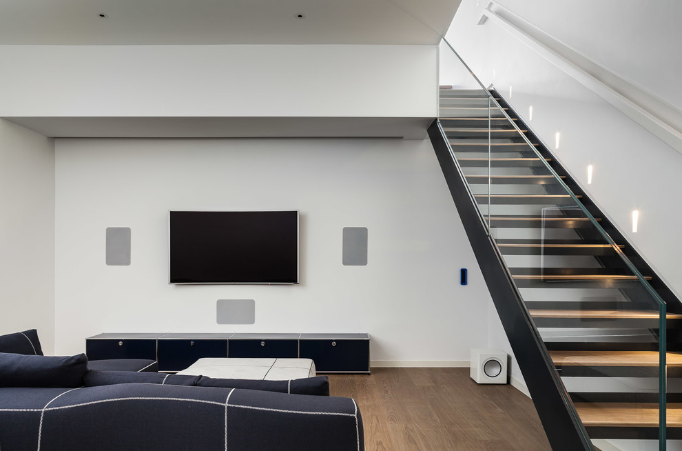 Mittelgroßes, Offenes Modernes Heimkino mit weißer Wandfarbe, hellem Holzboden und Multimediawand in London