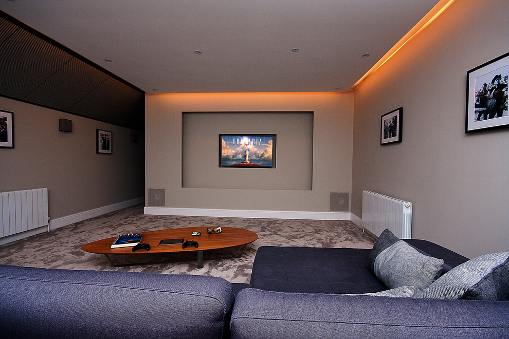 На фото: изолированный домашний кинотеатр среднего размера в стиле модернизм с бежевыми стенами, ковровым покрытием, телевизором на стене и серым полом с