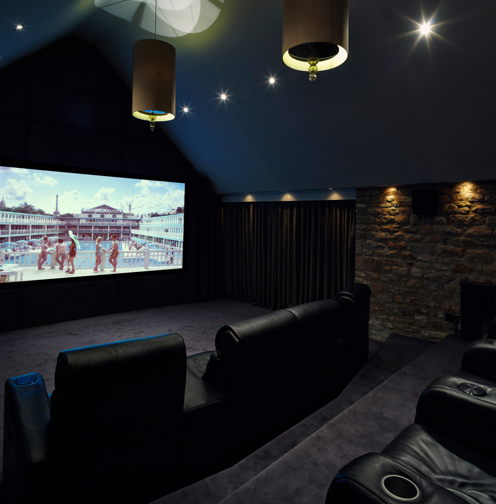 Idée de décoration pour une grande salle de cinéma design avec un sol noir.