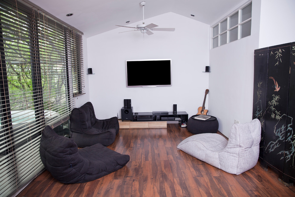 Idee per un home theatre contemporaneo di medie dimensioni con pareti bianche, pavimento in legno massello medio e TV a parete