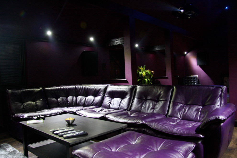 Foto di un grande home theatre design aperto con pareti viola, pavimento in legno massello medio e schermo di proiezione