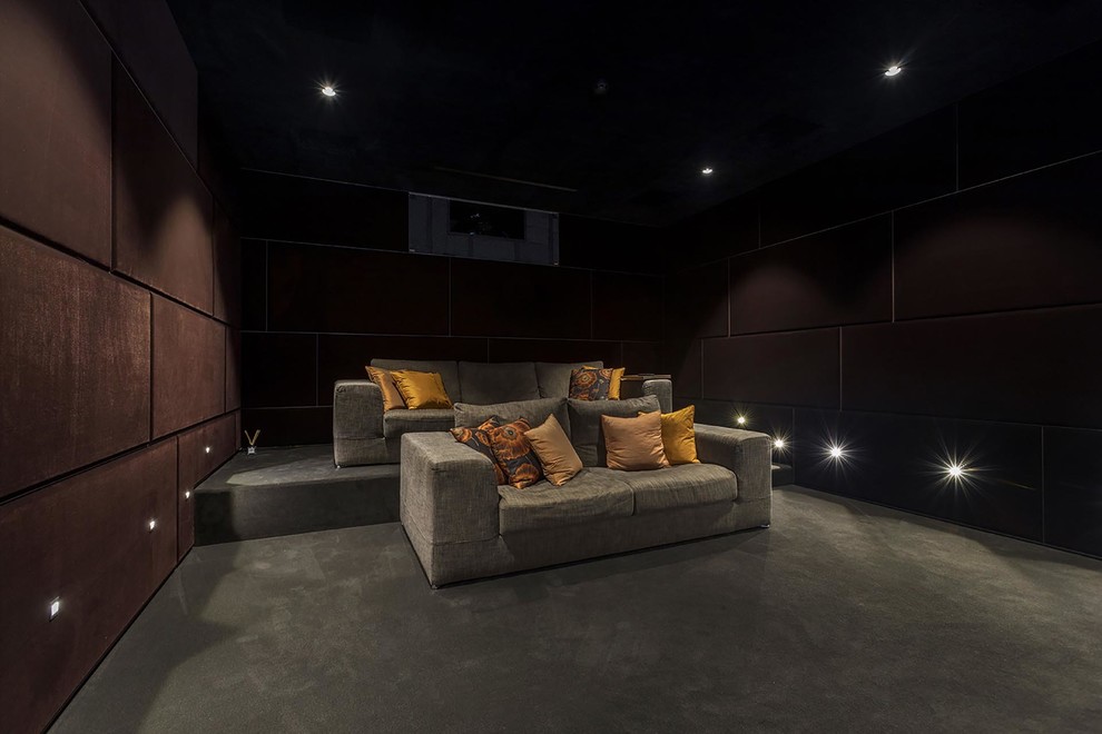 Cette image montre une salle de cinéma minimaliste de taille moyenne et fermée avec un mur rouge, moquette, un écran de projection et un sol gris.