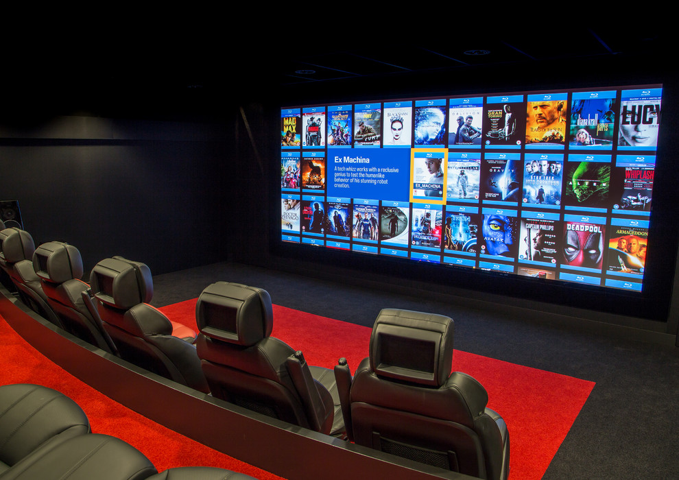 Réalisation d'une grande salle de cinéma design avec un mur multicolore, moquette et un écran de projection.