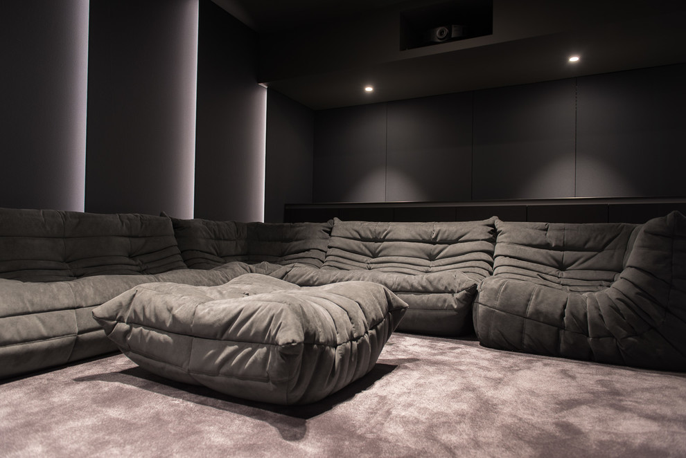Cette photo montre une salle de cinéma tendance de taille moyenne et fermée avec un mur violet, moquette, un écran de projection et un sol gris.