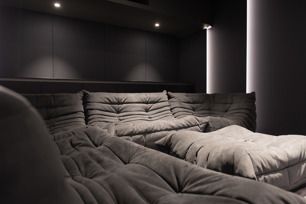 Cette image montre une salle de cinéma design de taille moyenne et fermée avec un mur violet, moquette, un écran de projection et un sol gris.