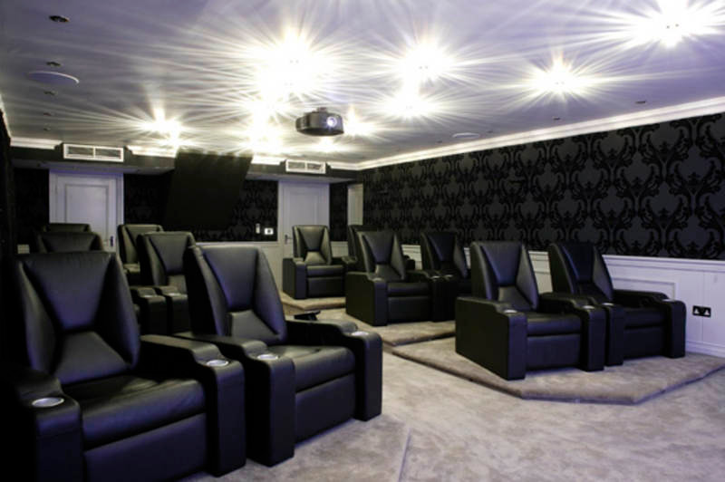 Photo of a large contemporary enclosed home cinema in Other with black walls, carpet and a wall mounted tv.