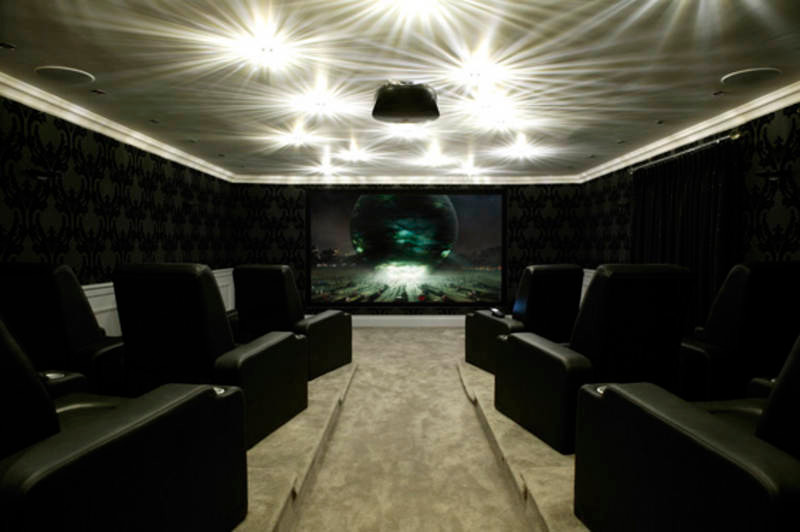 Immagine di un grande home theatre contemporaneo chiuso con pareti nere, moquette e TV a parete