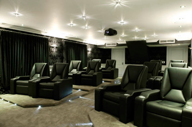 Photo of a large contemporary enclosed home cinema in Other with black walls, carpet and a wall mounted tv.