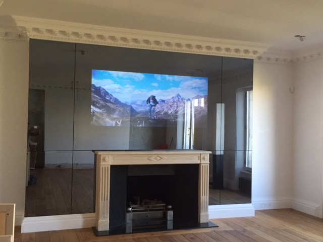 Imagen de cine en casa cerrado clásico renovado extra grande con suelo de madera clara y televisor colgado en la pared