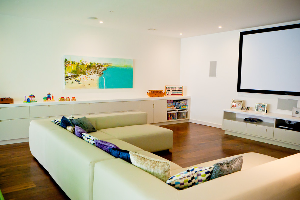 Example of a trendy open concept dark wood floor home theater design in London with white walls