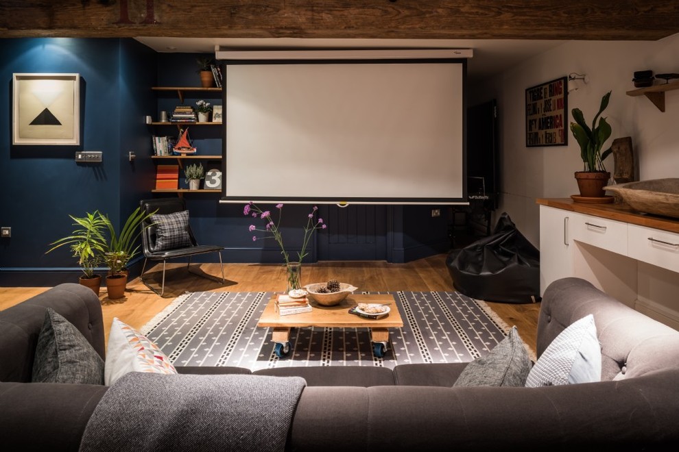 Diseño de cine en casa cerrado costero de tamaño medio con paredes azules, suelo de madera en tonos medios, pantalla de proyección y suelo beige