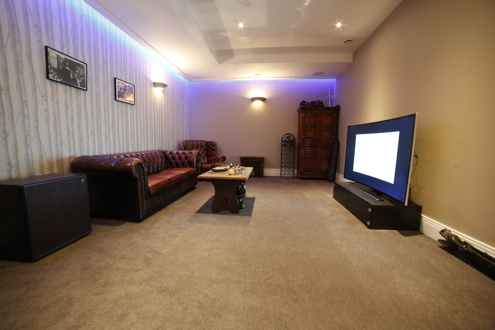 Modelo de cine en casa cerrado moderno pequeño con paredes beige, moqueta y televisor colgado en la pared