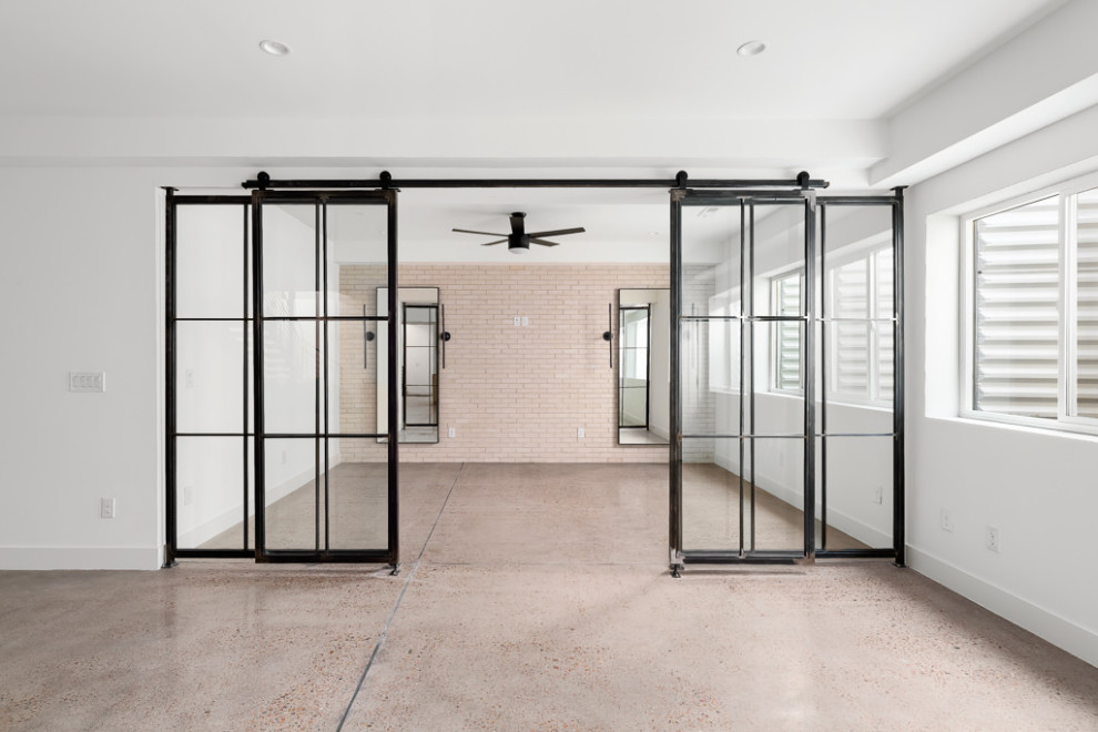 Imagen de gimnasio multiusos minimalista con paredes blancas, suelo de cemento y suelo gris