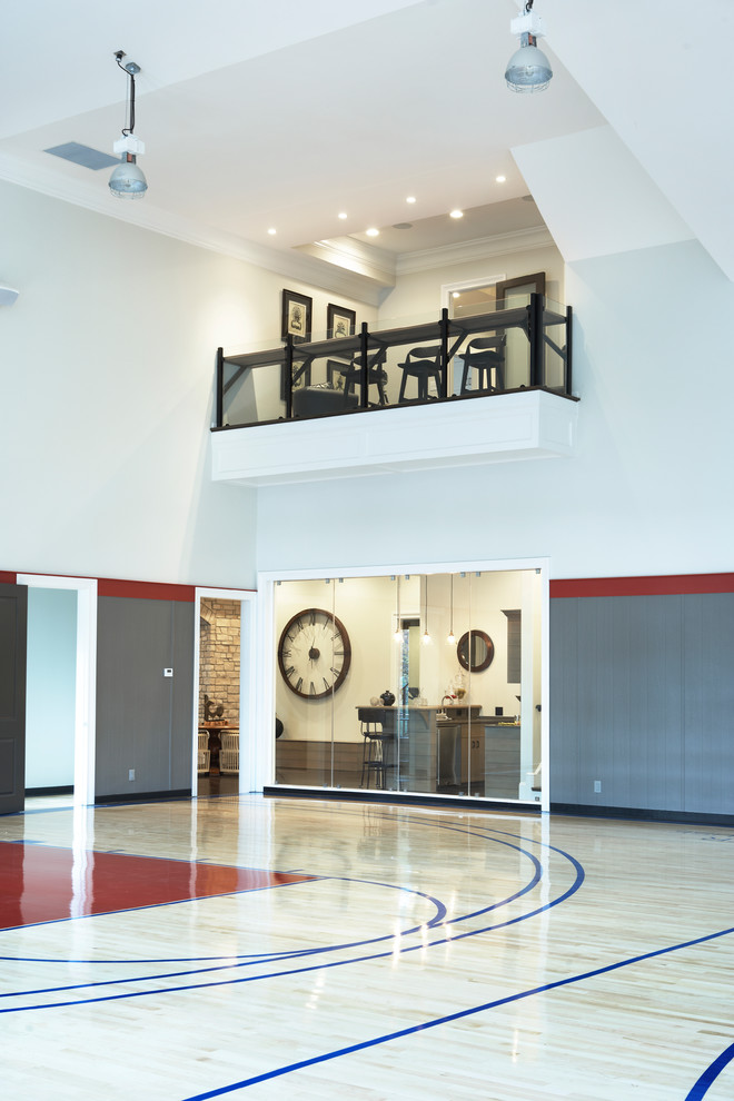 Geräumiger Moderner Fitnessraum mit Indoor-Sportplatz, weißer Wandfarbe und hellem Holzboden in Sonstige