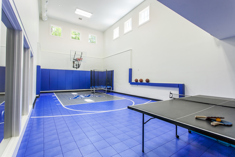 Cette image montre un terrain de sport intérieur traditionnel avec un mur blanc et un sol bleu.