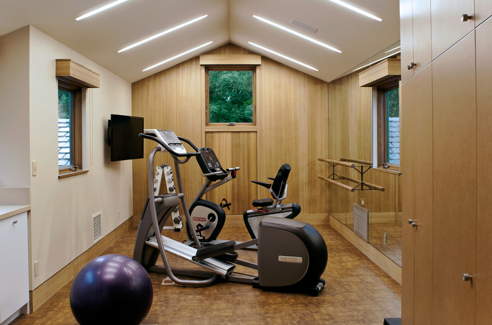 This is an example of a small contemporary home gym with beige walls and feature lighting.