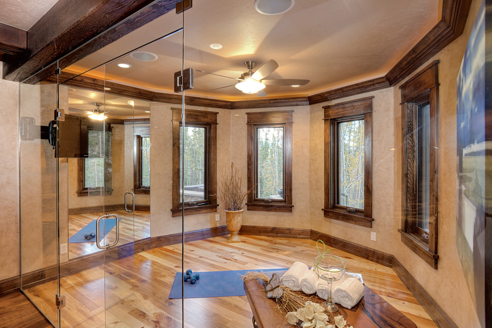 Klassisk inredning av ett hemmagym med yogastudio, med beige väggar, ljust trägolv och brunt golv