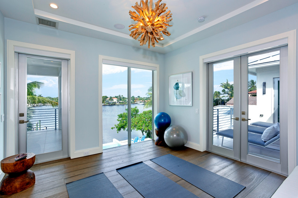 Mittelgroßer Moderner Yogaraum mit blauer Wandfarbe, dunklem Holzboden und braunem Boden in Miami