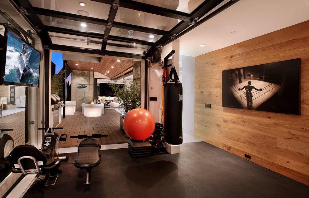 Contemporary multi-use home gym in Orange County with black floors and a feature wall.