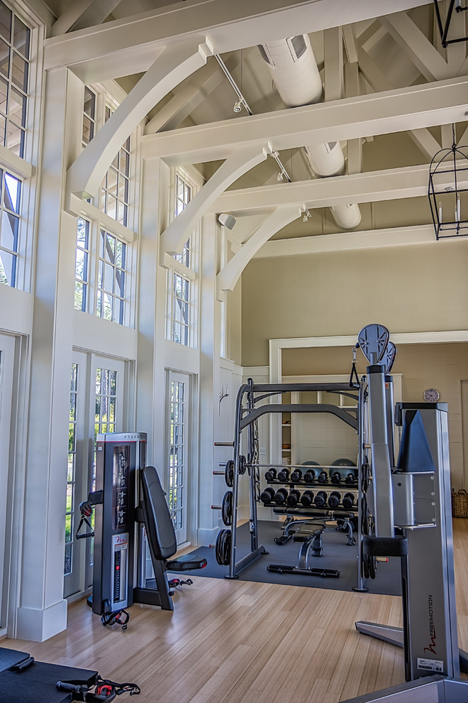 Imagen de sala de pesas contemporánea grande con paredes beige, suelo de madera clara y suelo marrón