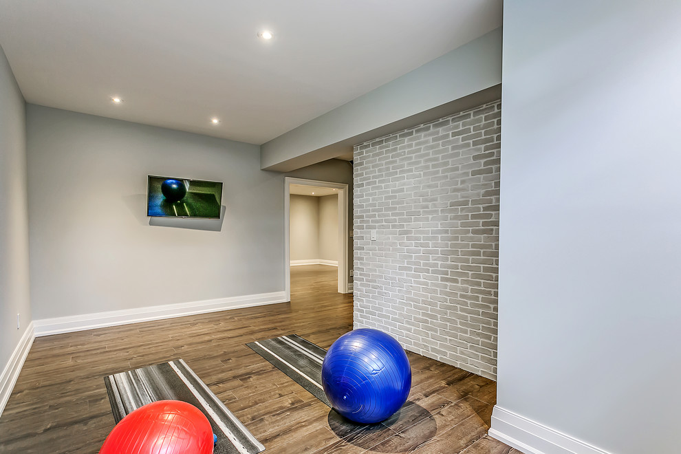 Idée de décoration pour un studio de yoga design de taille moyenne avec un mur gris, parquet foncé et un sol marron.