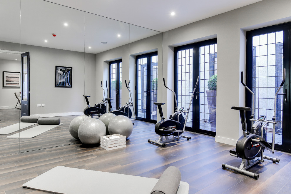 Klassischer Fitnessraum mit grauer Wandfarbe, dunklem Holzboden und braunem Boden in Hertfordshire